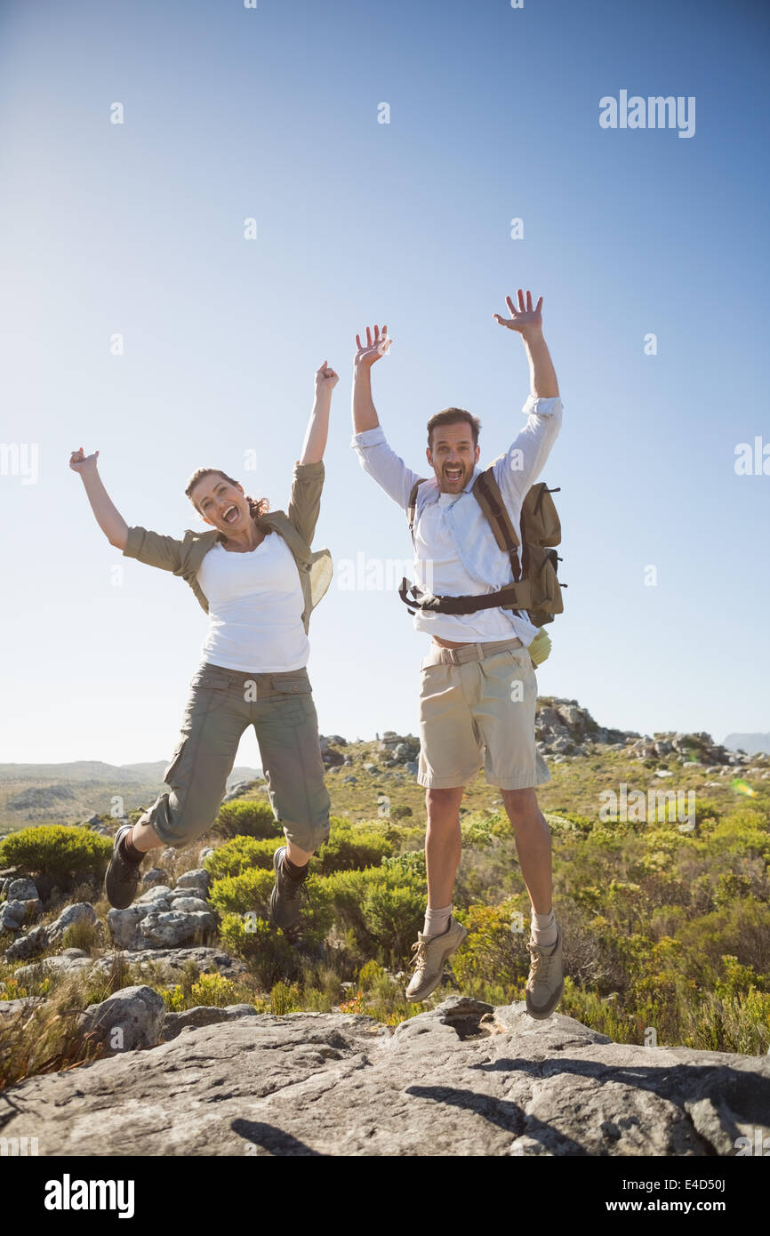 Escursionismo coppia di salto e a fare il tifo per terreni rocciosi Foto Stock