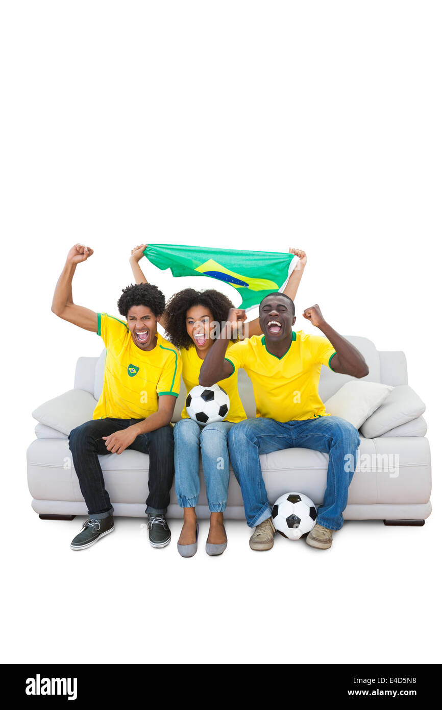 Il brasiliano gli appassionati di calcio in giallo a fare il tifo per il divano Foto Stock