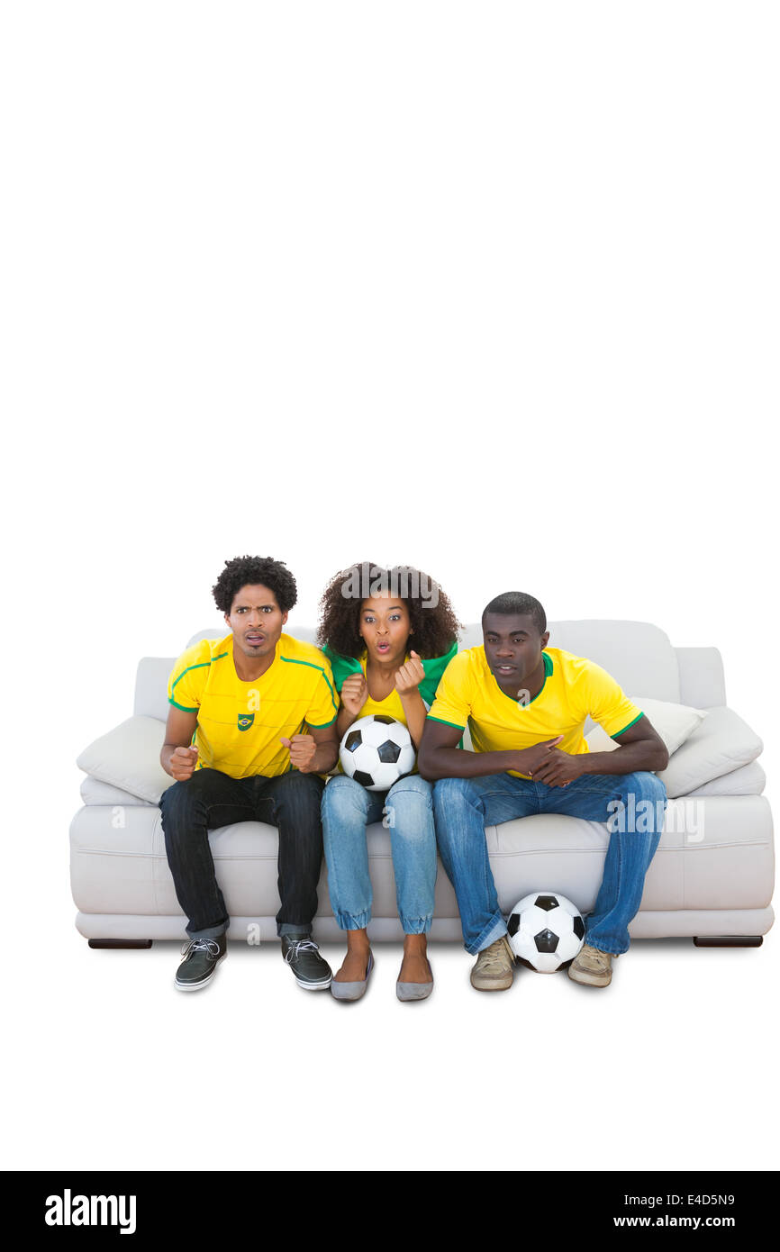 Brasiliano nervoso i tifosi di calcio in giallo sul divano Foto Stock