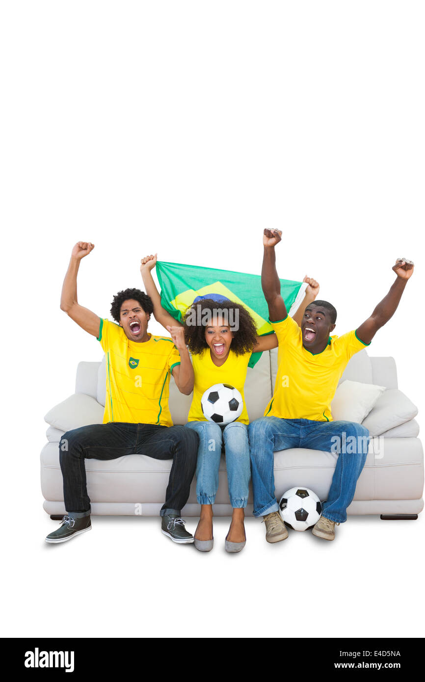Il tifo brasiliano per gli appassionati di calcio in giallo sul divano Foto Stock