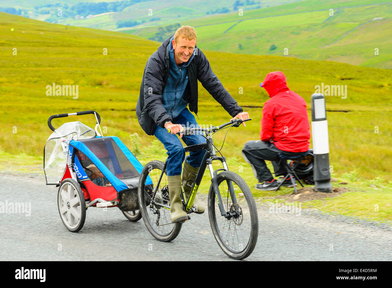Ciclista con rimorchio per bambini in attesa dell arrivo del 2014 Tour de France prima tappa su Buttertubs Pass North Yorkshire Foto Stock