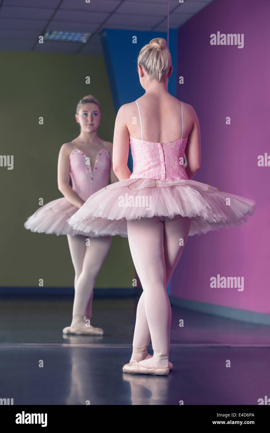 Graziosa ballerina in piedi in prima posizione nella parte anteriore dello specchio Foto Stock