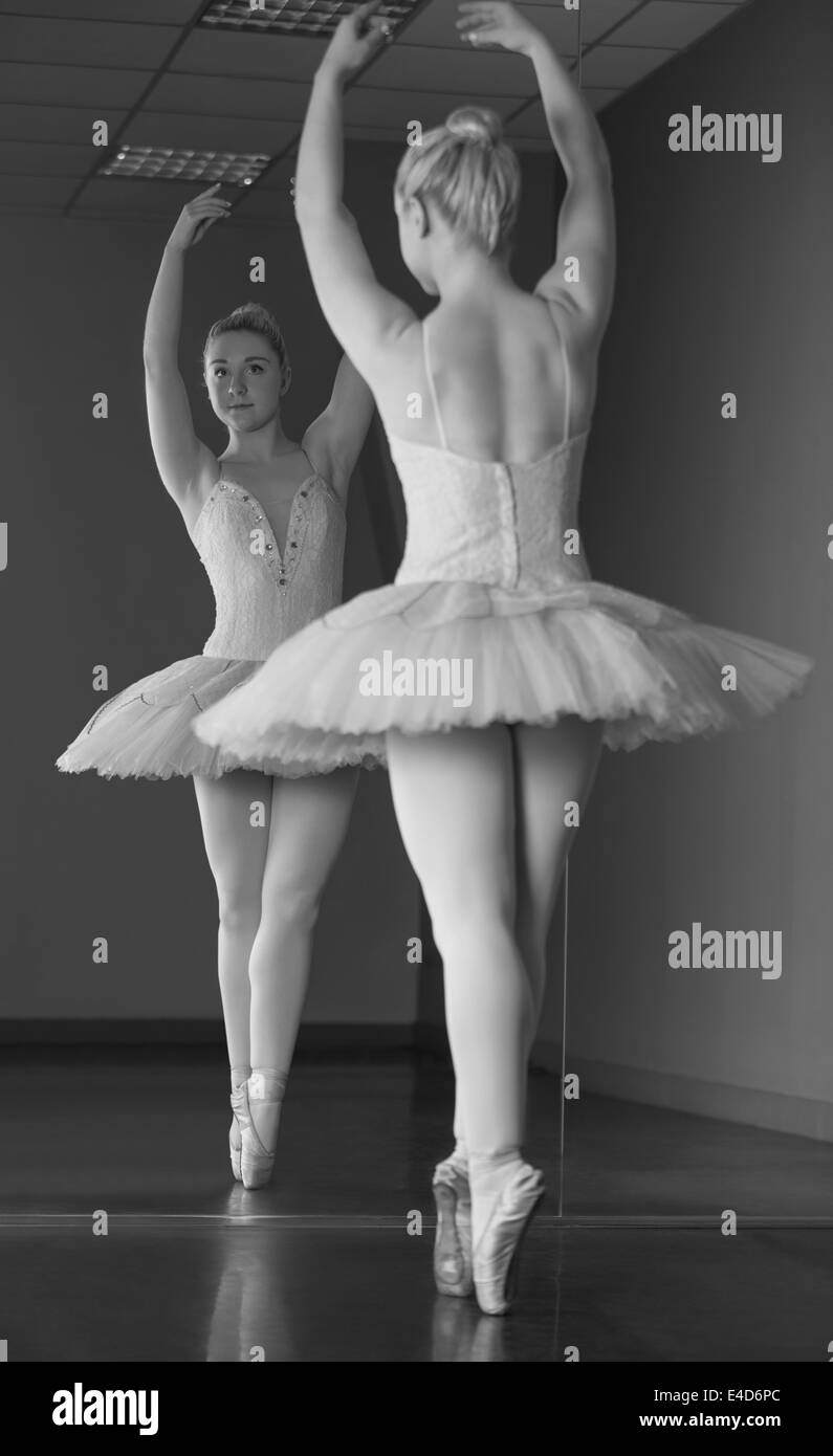 Graziosa ballerina in piedi en pointe nella parte anteriore dello specchio Foto Stock
