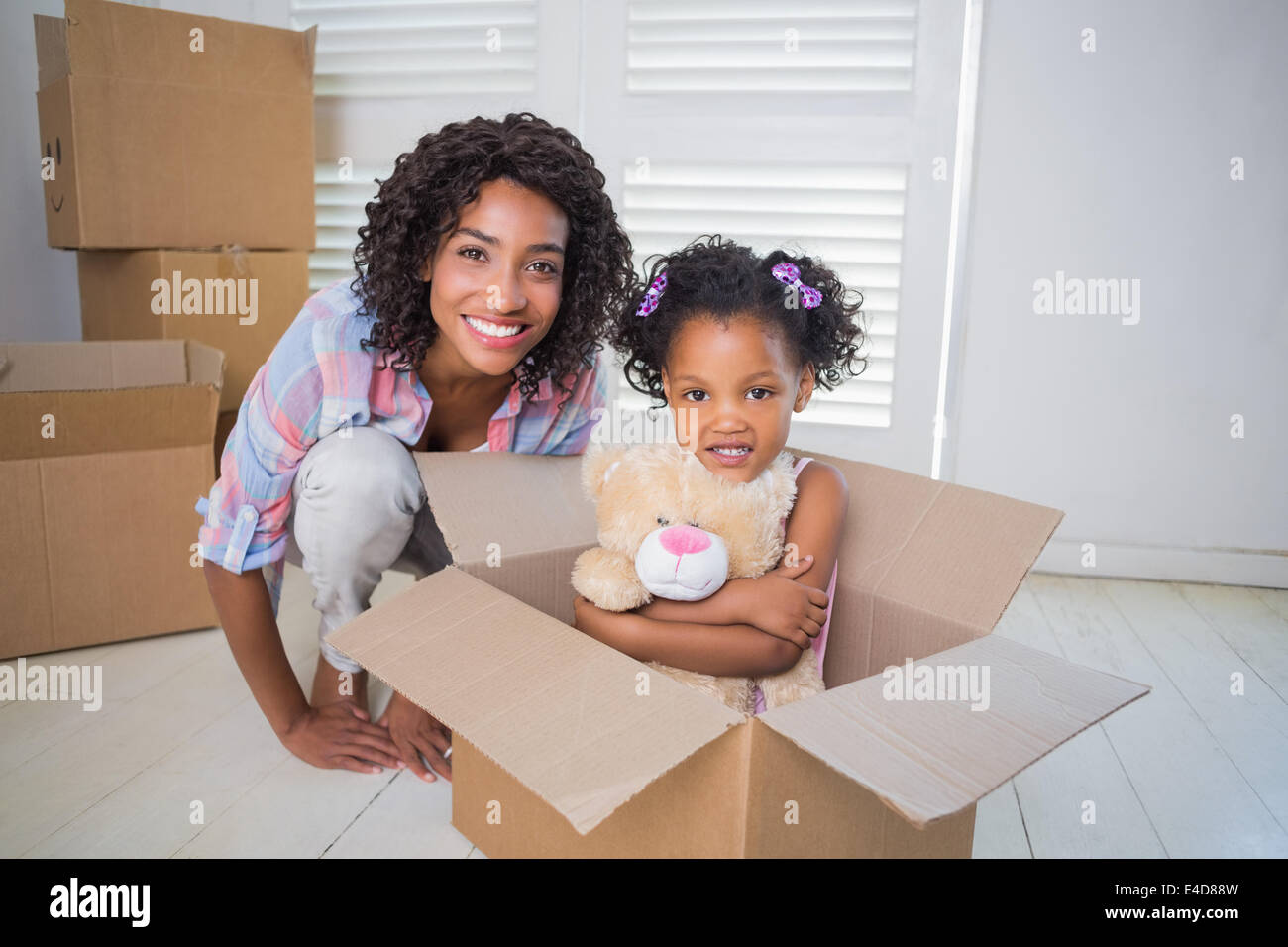 Carino figlia seduta nella scatola di movimentazione con la madre Foto Stock