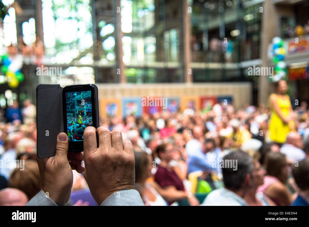 Molti genitori in una highschool insieme per celebrare gli studiosi che hanno superato gli esami. Un genitore di catturare con il suo smartphone Foto Stock