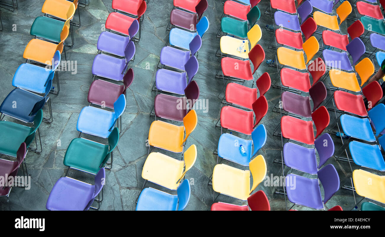 Righe di colorati e svuotare le sedie in plastica in una scuola Foto Stock