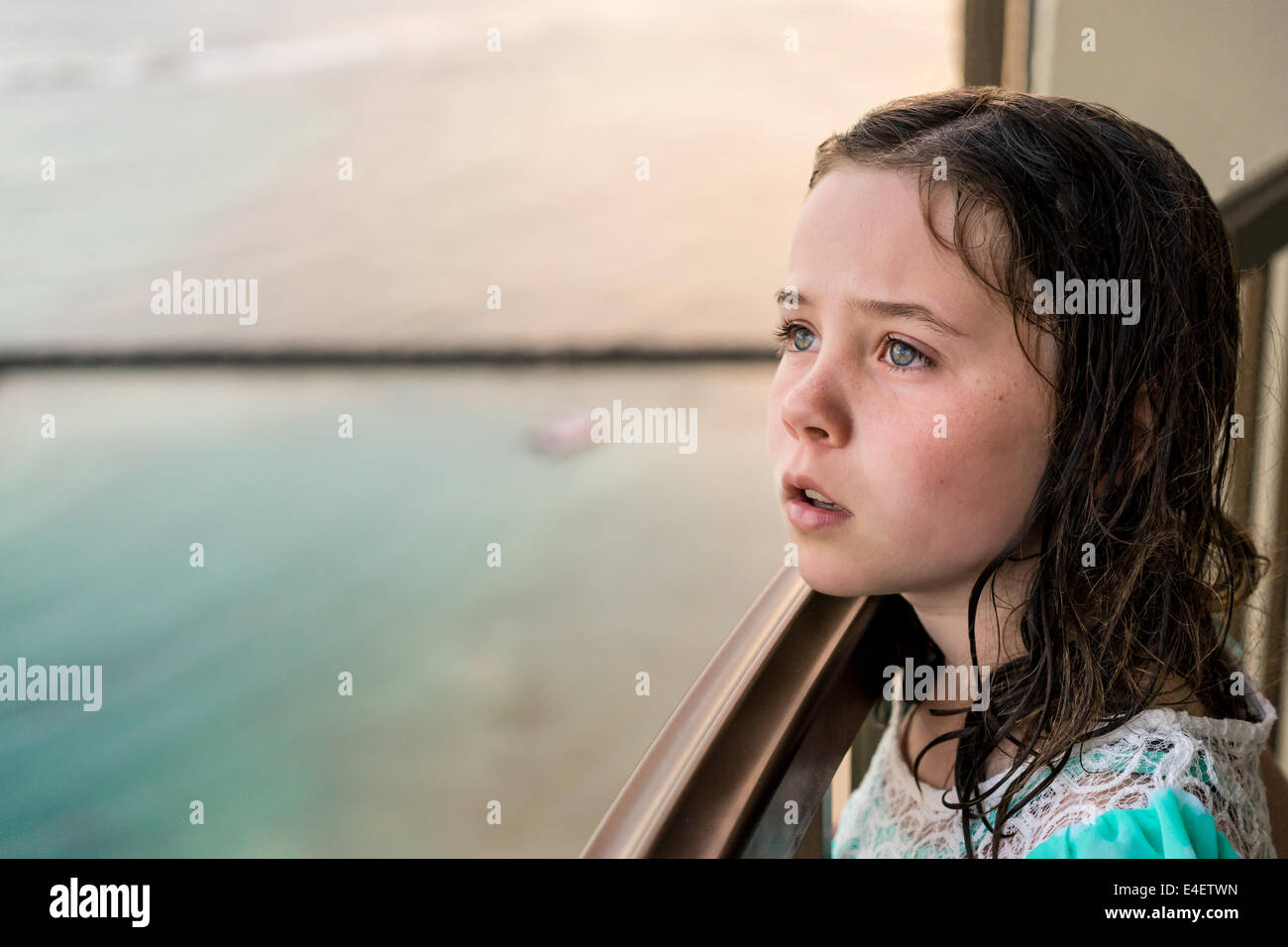 Bambina guarda in distanza con acqua blu in background. Foto Stock