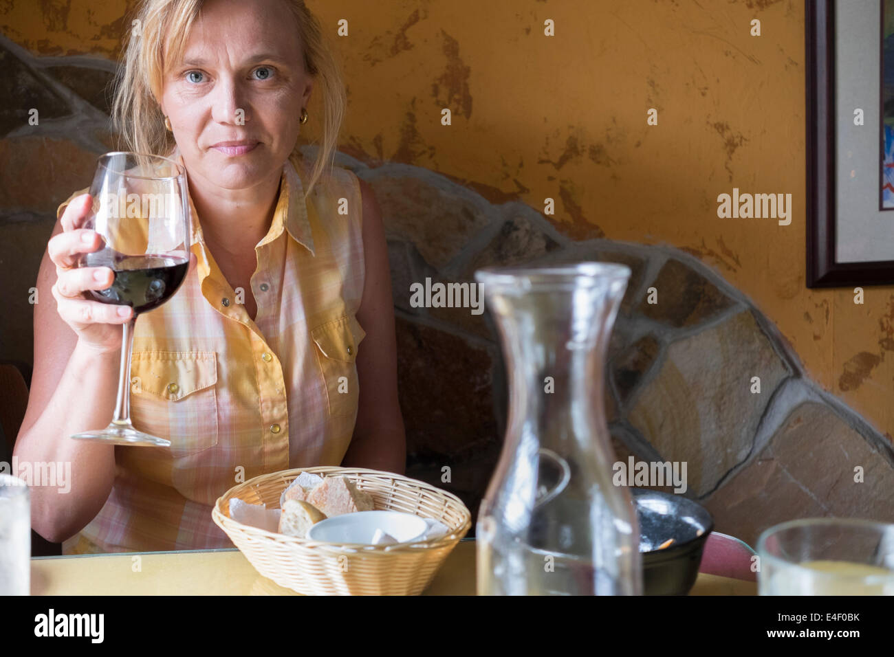 Tabella italiano impostazione con un paniere di Ciabatta pane e olio di oliva. Una donna sta bevendo vino rosso. Foto Stock