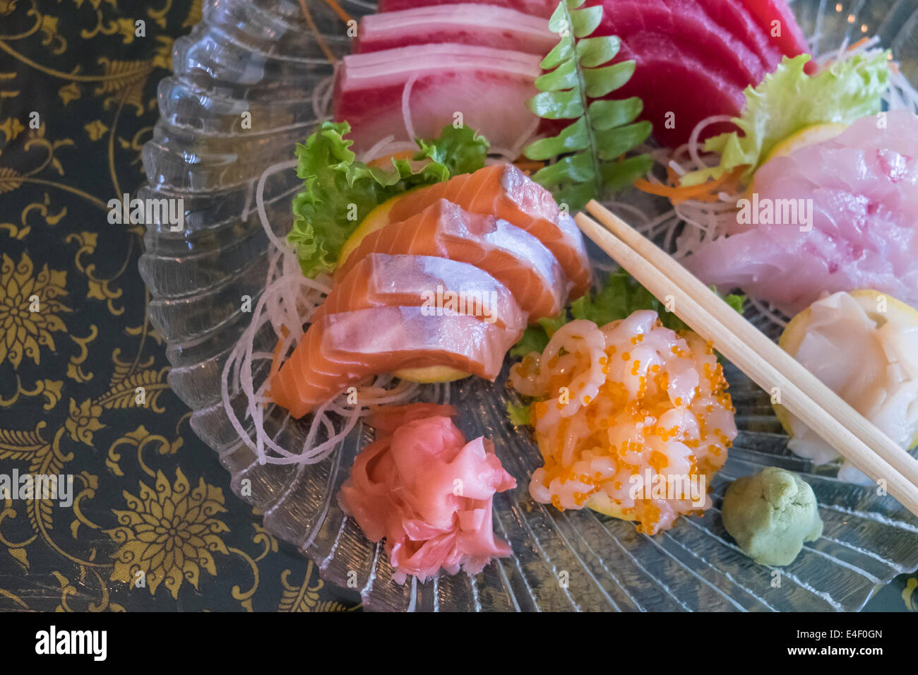 Lastra di vetro con il sashimi varietà di fettine di salmone crudo, red snapper, filetto di tonno, roe caviale uova di pesce, coda gialla, wasabi Foto Stock