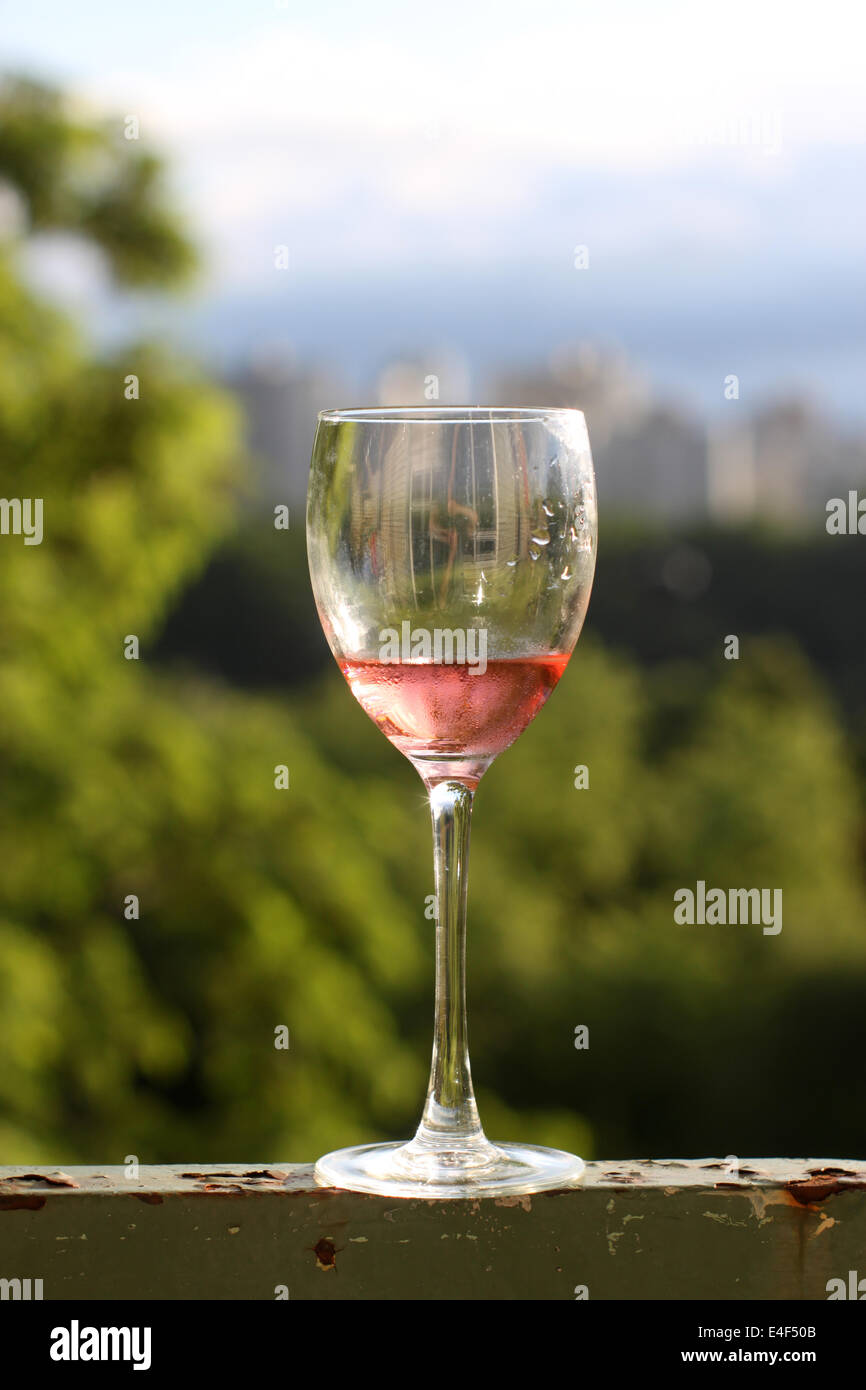Un bicchiere di vino rosato su una ringhiera arrugginito Foto Stock