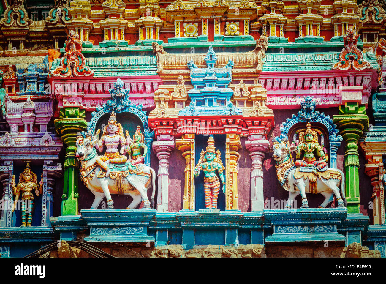 Vintage retrò hipster stile immagine di viaggio di Shiva e Parvati del Bull su immagini. Sculture sul tempio indù gopura (torre) Foto Stock
