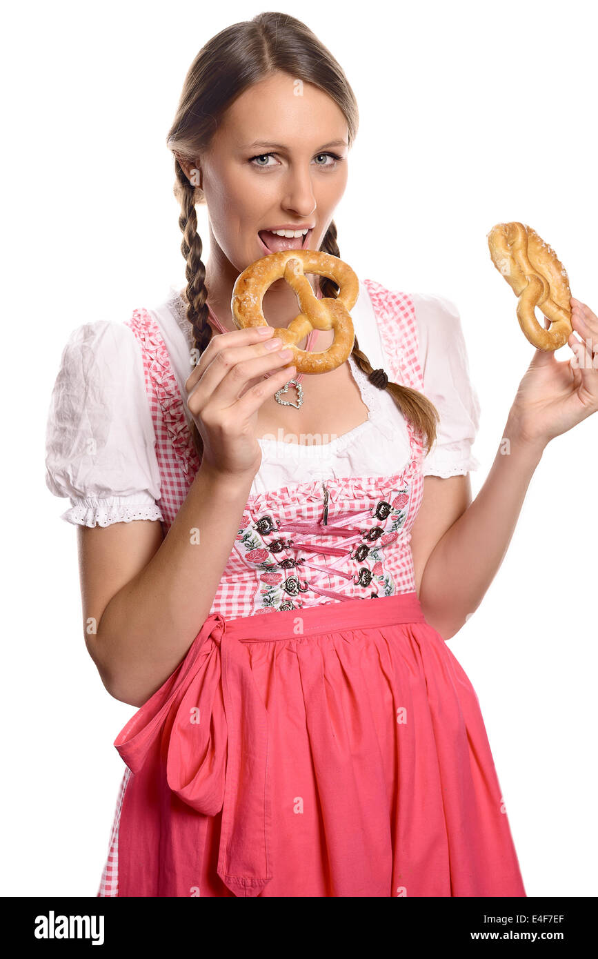 Felice attraente tedesco o donna bavarese in una tradizionale dirndl aprendo la bocca per mangiare un fresco pretzel Foto Stock