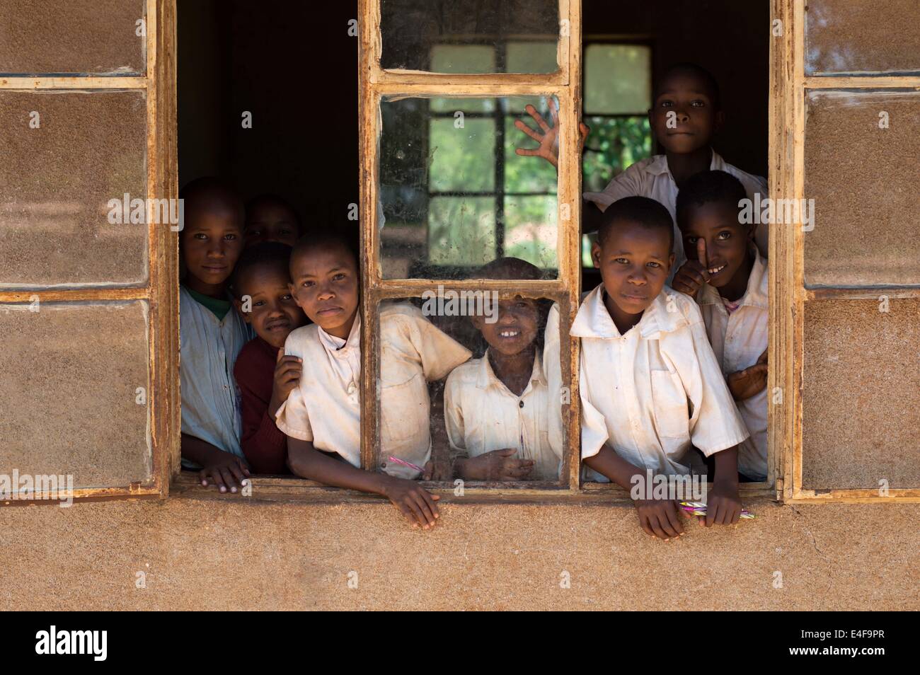Ritratto di gruppo di bambini di una scuola a distanza in Tanzania Africa guardando fuori dalla finestra Foto Stock