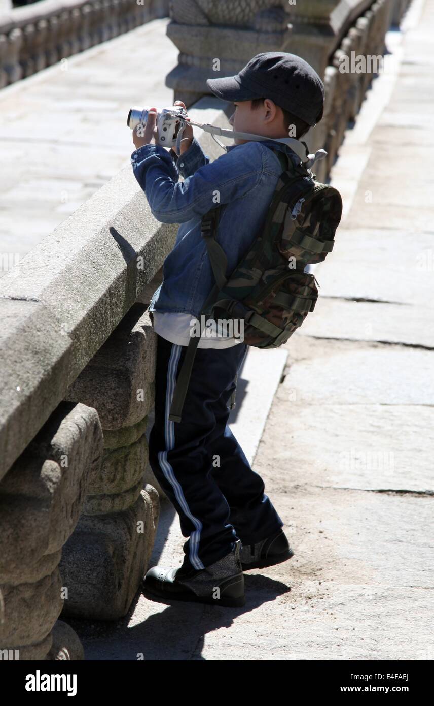 Si tratta di una foto di un bambino o ragazzo che sta parlando di un'immagine o una foto. Egli è al di fuori della strada vicino a un vecchio tempio di Seoul Foto Stock