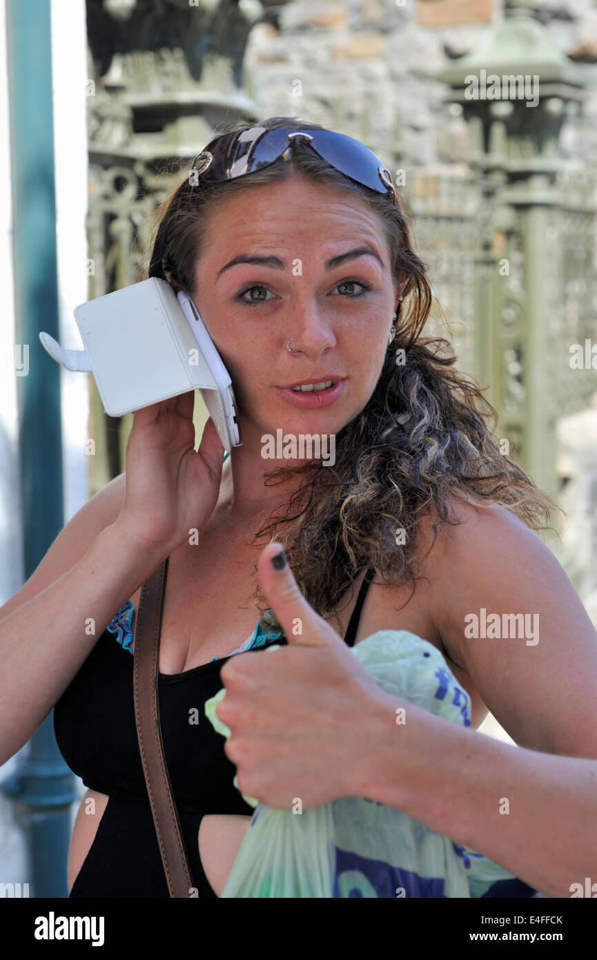 Donna che utilizza il telefono cellulare e dando il pollice in alto segno Foto Stock