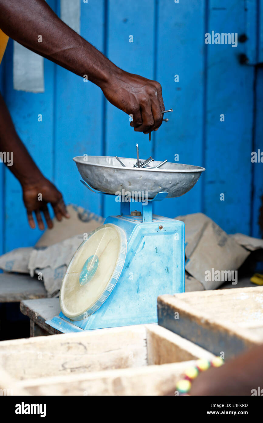 Falegname africana pesa chiodi su una scala blu Foto Stock