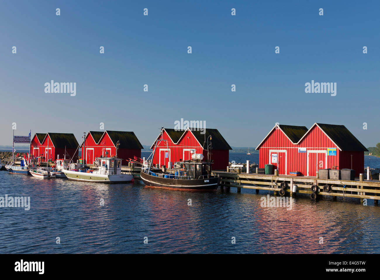 Barche da pesca ormeggiate nella parte anteriore del rosso capanne in legno nel porto di Boltenhagen lungo il Mar Baltico, Meclenburgo-Pomerania Occidentale, Ger Foto Stock