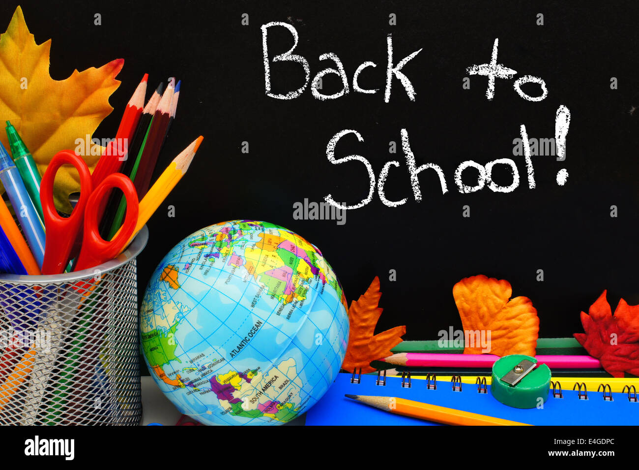 Si torna a scuola scritto su una lavagna con forniture scolastiche Foto Stock