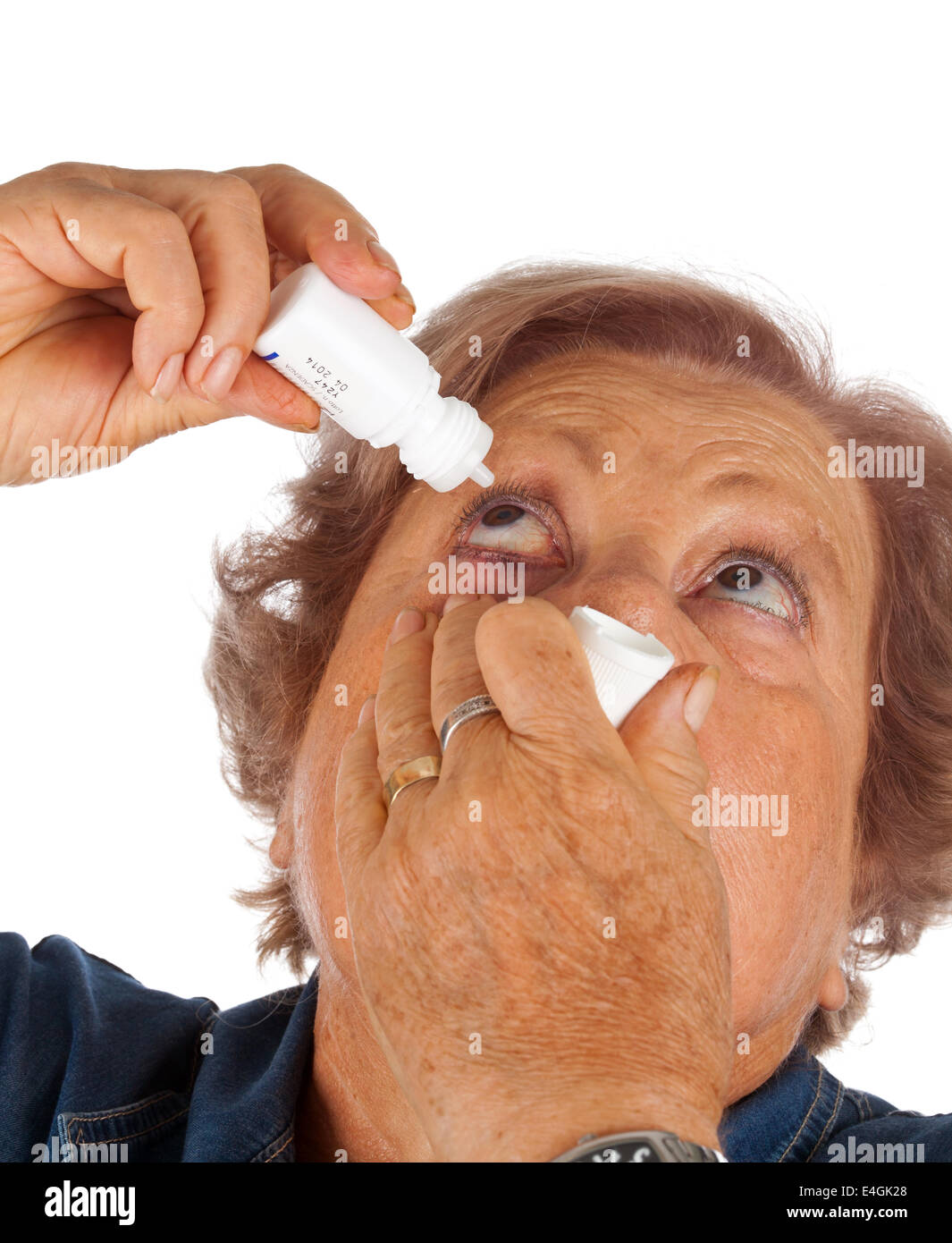 Donna anziana applicando gocce per gli occhi su sfondo bianco Foto Stock