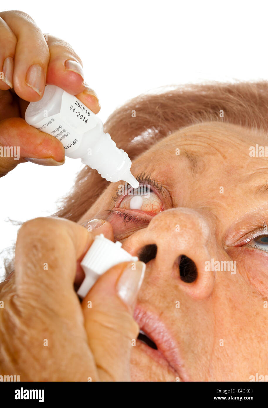 Donna anziana applicando gocce per gli occhi su sfondo bianco Foto Stock