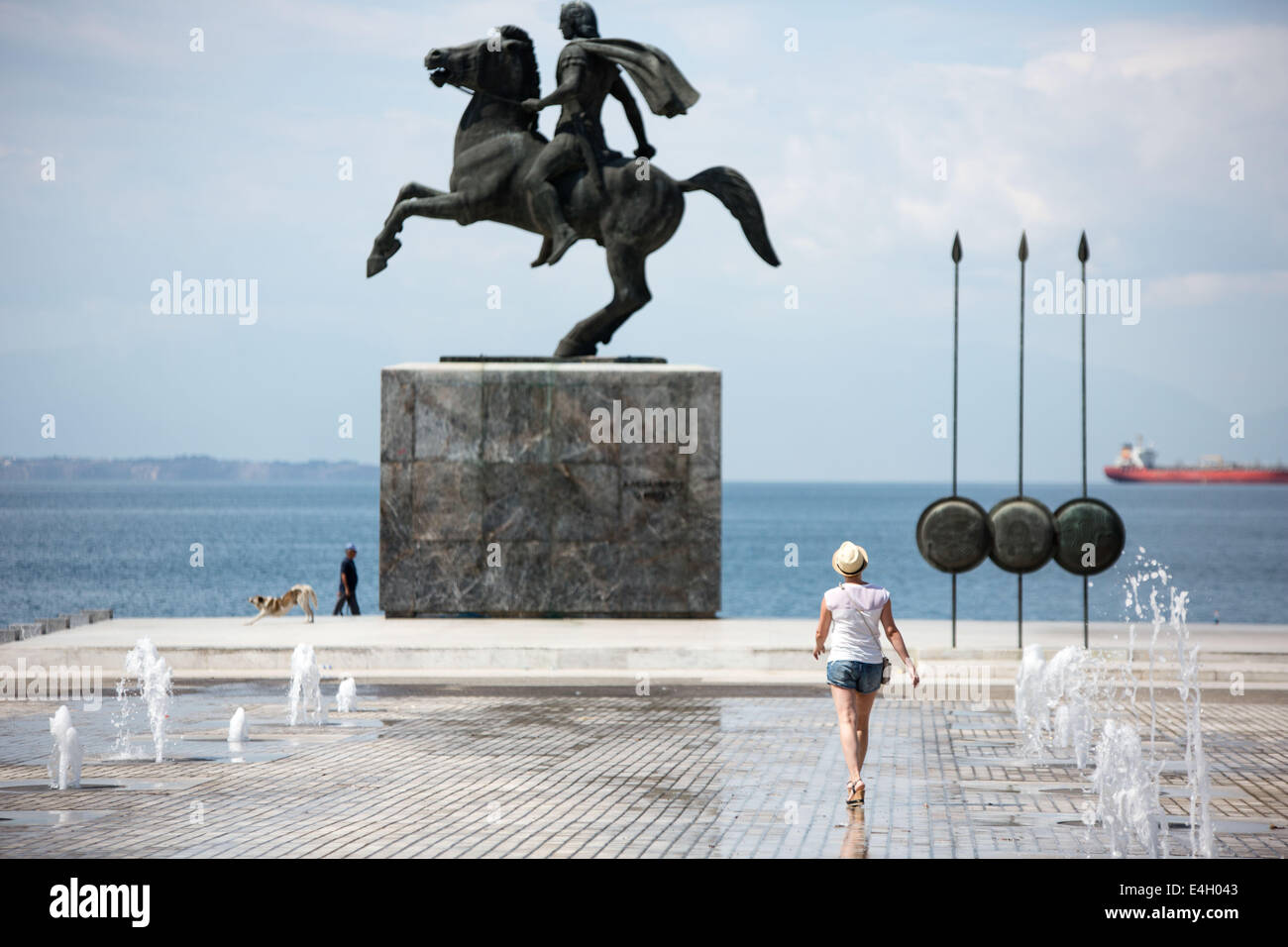 Salonicco, Grecia. 11 luglio 2014. Tourist davanti alla statua di Alessandro il Grande e il suo cavallo Bucephalus, durante una mattina di sole, nella città di Salonicco, Grecia. L'Associazione del turismo greco imprese (SETE) ha aumentato la sua stima per gli arrivi turistici internazionali nel 2014 a 19 milioni di euro da 18,5 milioni dello scorso anno. Salonicco, Grecia sulla luglio 11, 2014. Credito: Konstantinos Tsakalidis/Alamy Live News Foto Stock