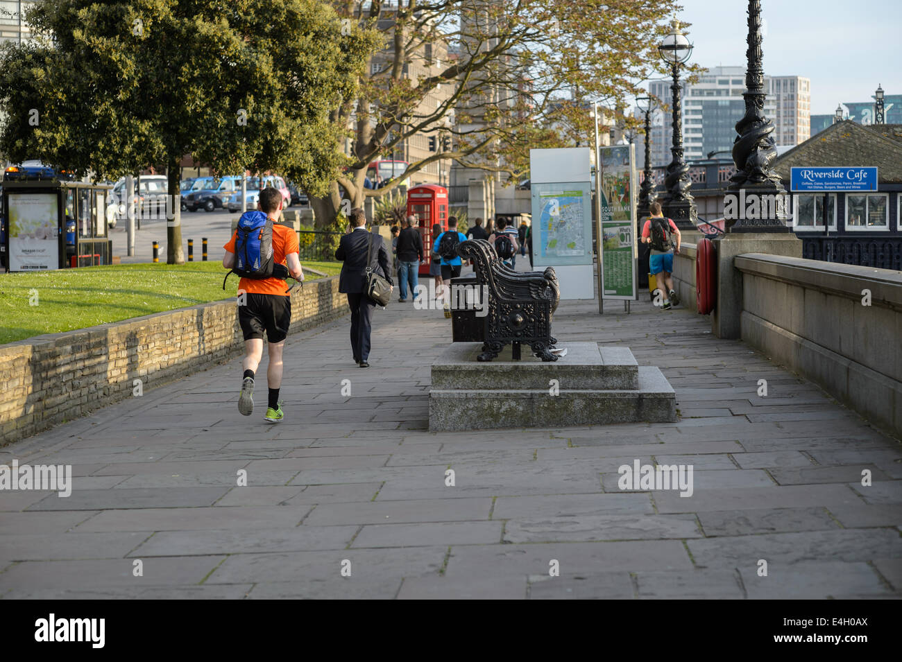 Un pareggiatore jogger corre eseguire in esecuzione a casa dal lavoro lungo la passeggiata sulla riva sud del Tamigi, Lambeth, London, Regno Unito Foto Stock