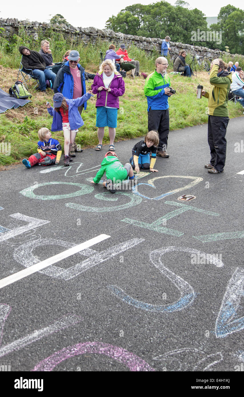 I bambini lo sfarinamento i nomi dei piloti su strada prima della data prevista di arrivo del Tour de France vicino Hawes, North Yorkshire, Inghilterra, Regno Unito Foto Stock