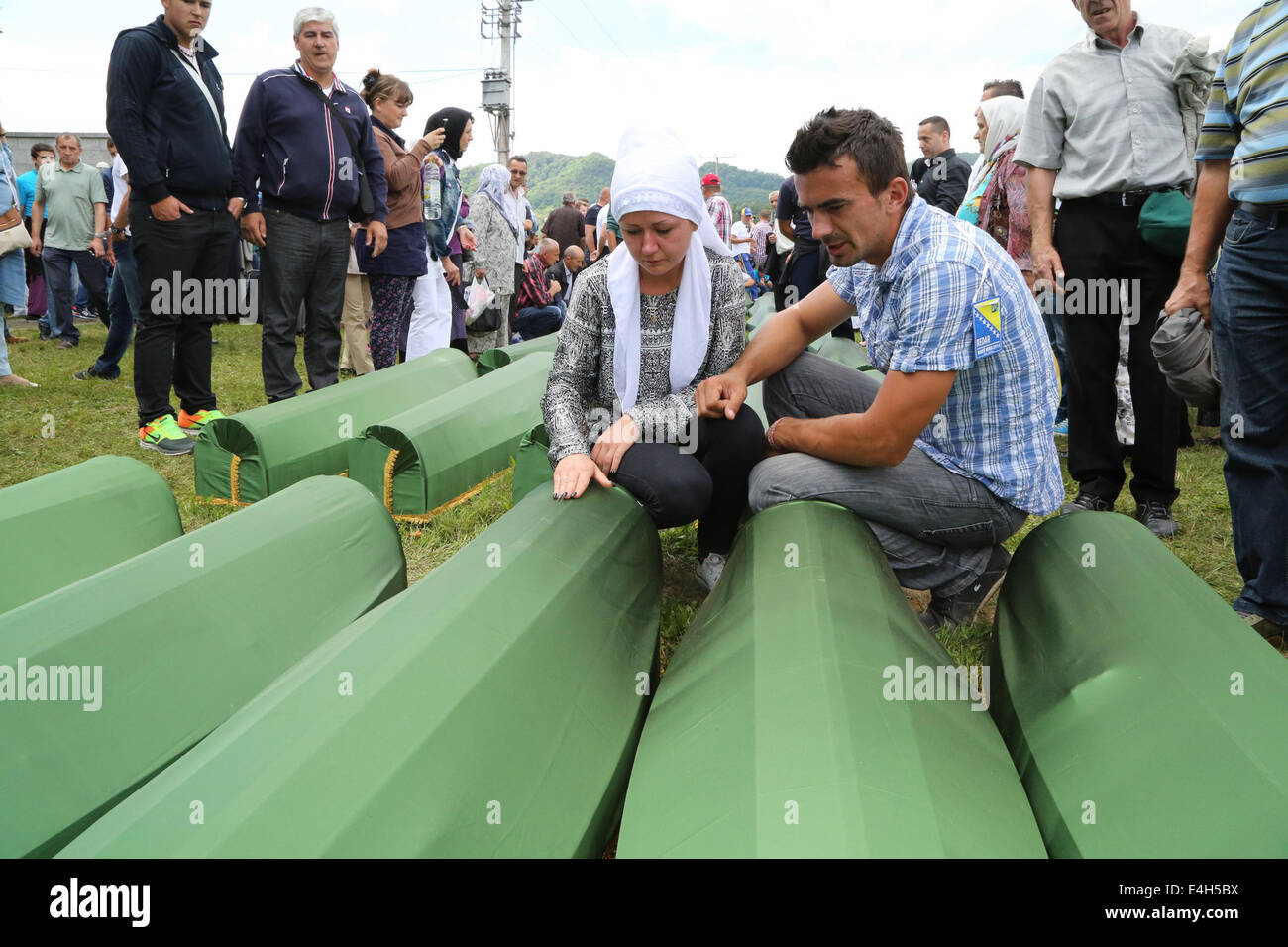 (140712) -- SREBRENICA, luglio 12, 2014 (Xinhua) -- parenti seduto accanto a bare delle vittime piangono prima di un funerale in Potocari, vicino a Srebrenica, Bosnia e Erzegovina, 11 luglio, 2014. Il funerale di 175 recentemente identificate le vittime si è tenuto qui Venerdì per commemorare il diciannovesimo anniversario del massacro di Srebrenica. Alcuni 7.000 uomini musulmani e i ragazzi sono stati massacrati in e vicino a Srebrenica dalle forze serbo-bosniache nel luglio 1995, il peggior massacro in Europa dalla fine della Seconda Guerra Mondiale. (Xinhua/Haris Memija) (zjl) Foto Stock