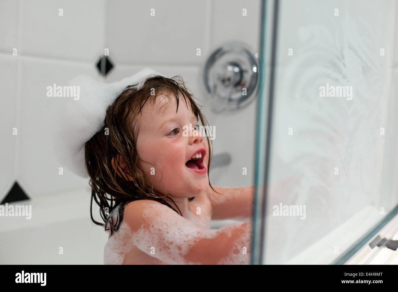 Ragazza che gioca in una vasca da bagno con bolle Foto Stock