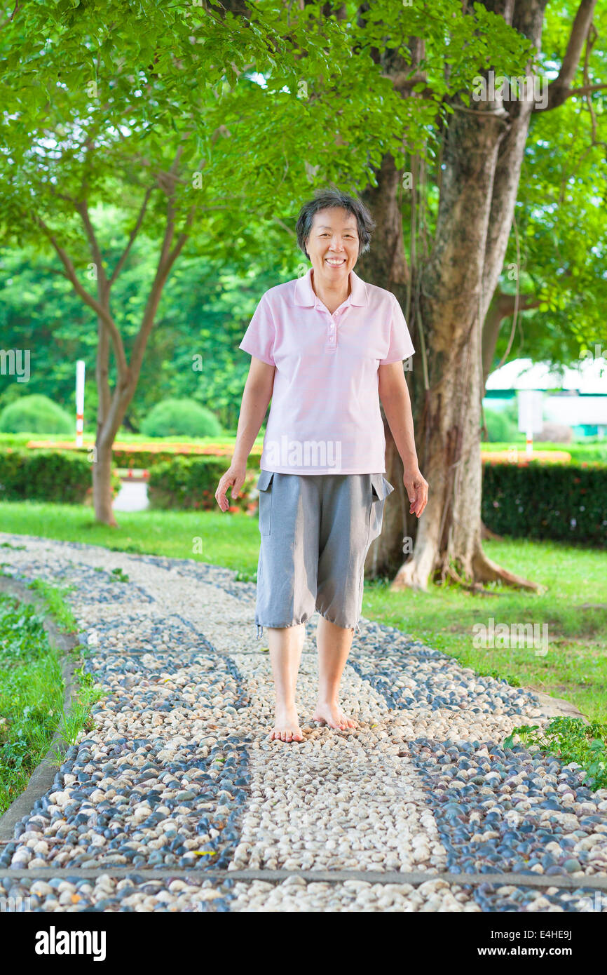 Asian donna anziana camminando sulla passerella di pietra Foto Stock