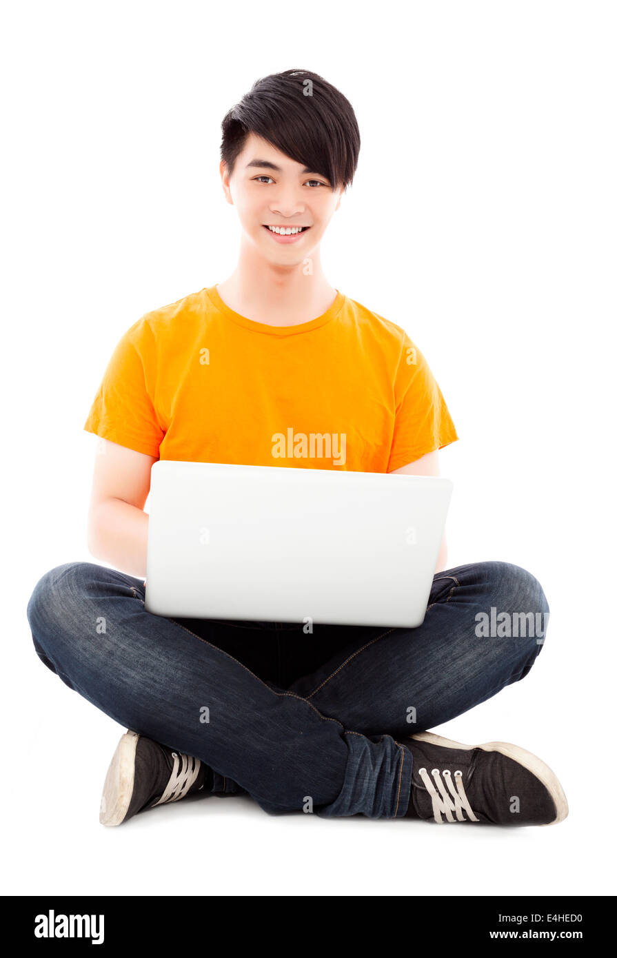 Felice giovane studente seduto sul pavimento e utilizzando computer portatile Foto Stock