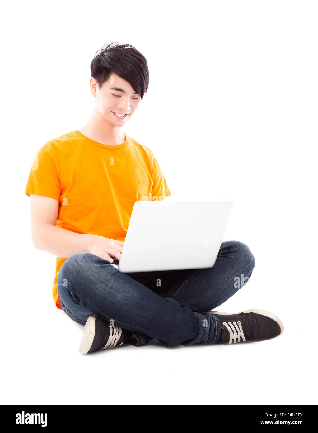 Sorridente giovane studente seduto sul pavimento e utilizzando computer portatile Foto Stock