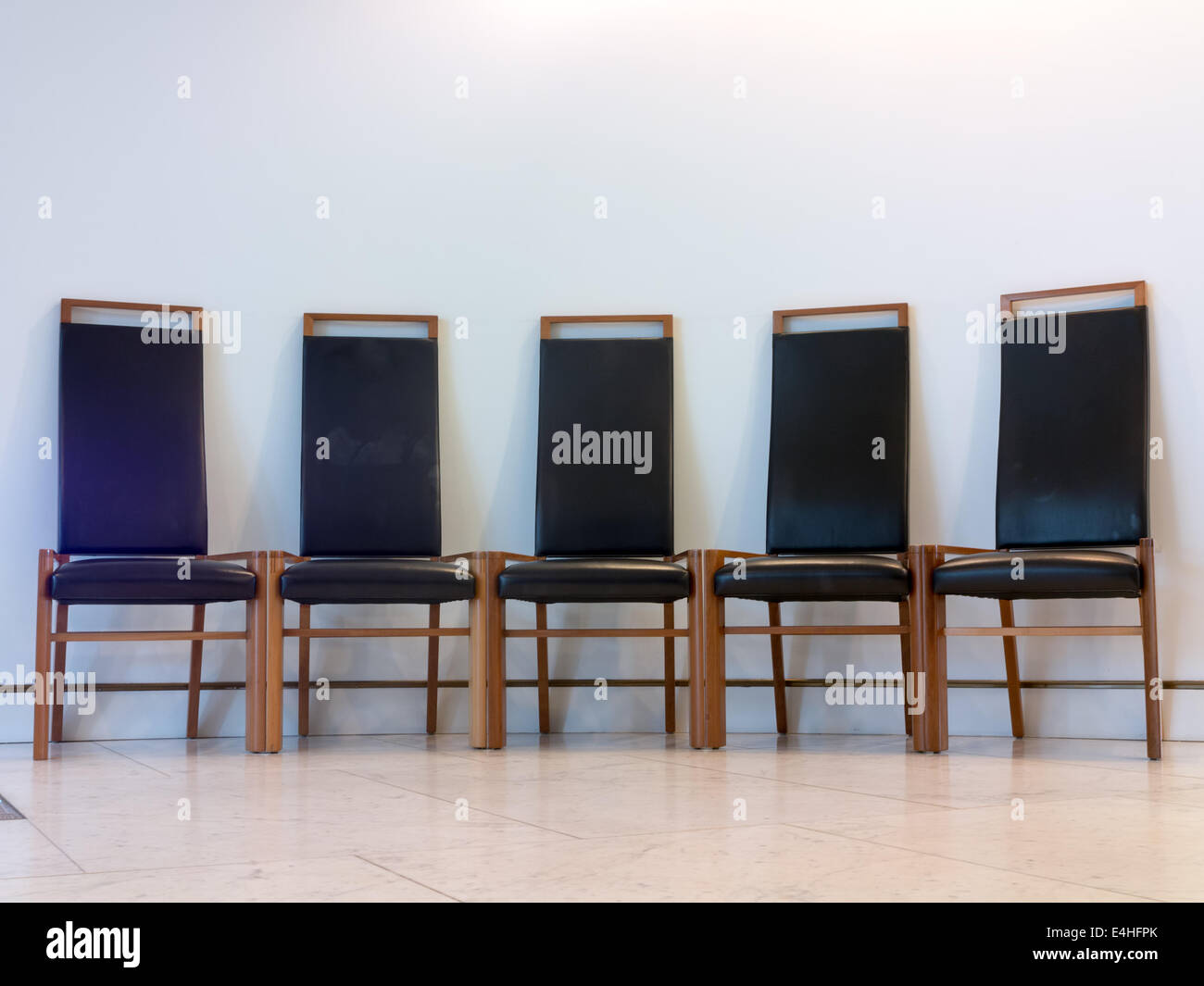 Gruppo di sedie disposte contro il muro bianco Foto Stock
