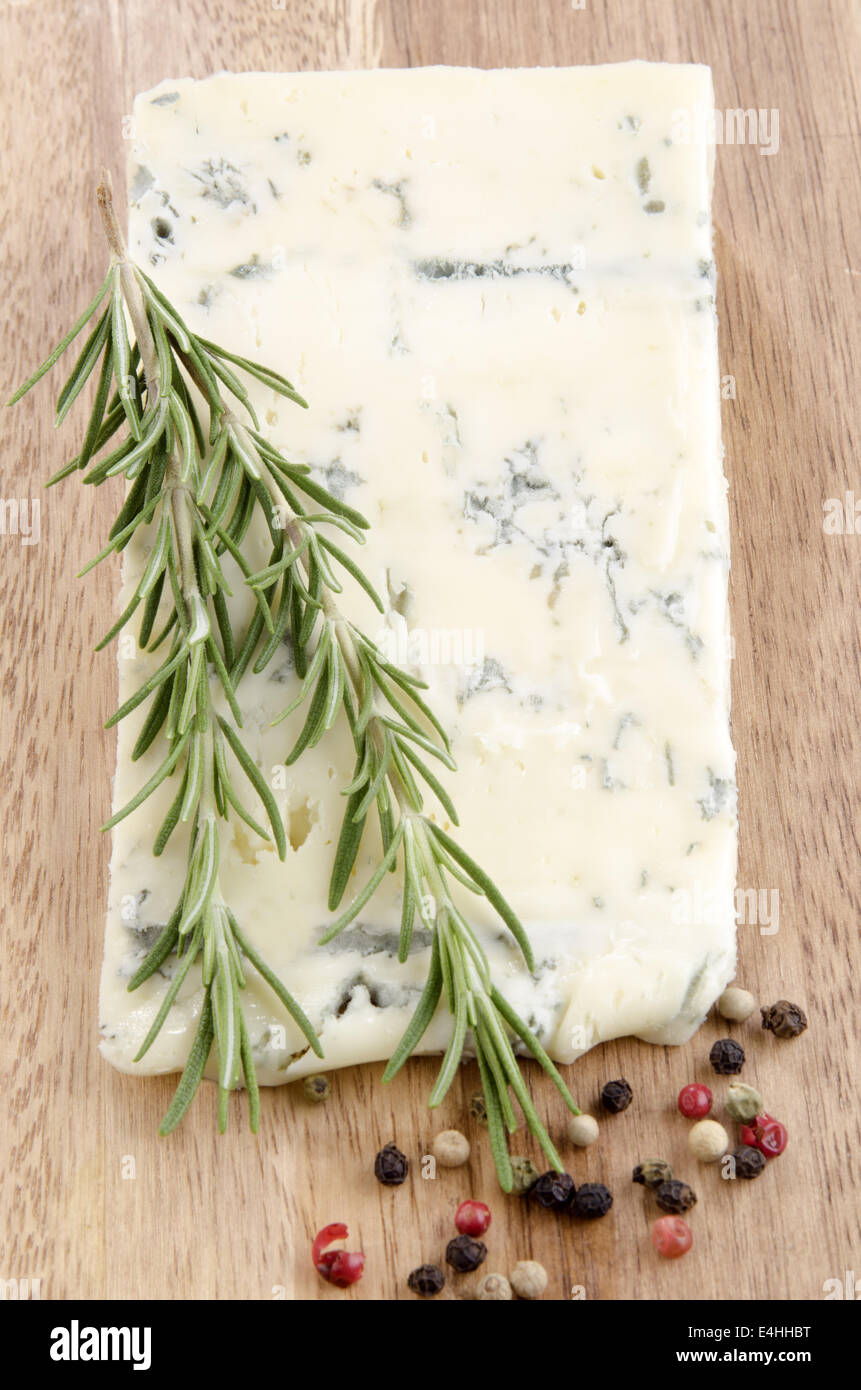 Formaggio Gorgonzola con pepe e rosmarino su una tavola di legno Foto Stock