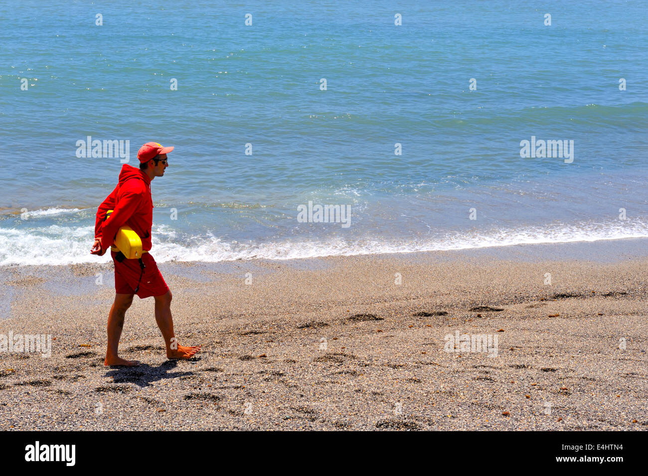 Bagnino di salvataggio con galleggiante spiaggia a piedi Foto Stock