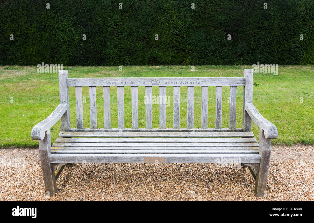 Panca in legno sede nei giardini di Sandringham House, Norfolk, inscritto "Queen Elizabeth II Silver Jubilee 1977' Foto Stock