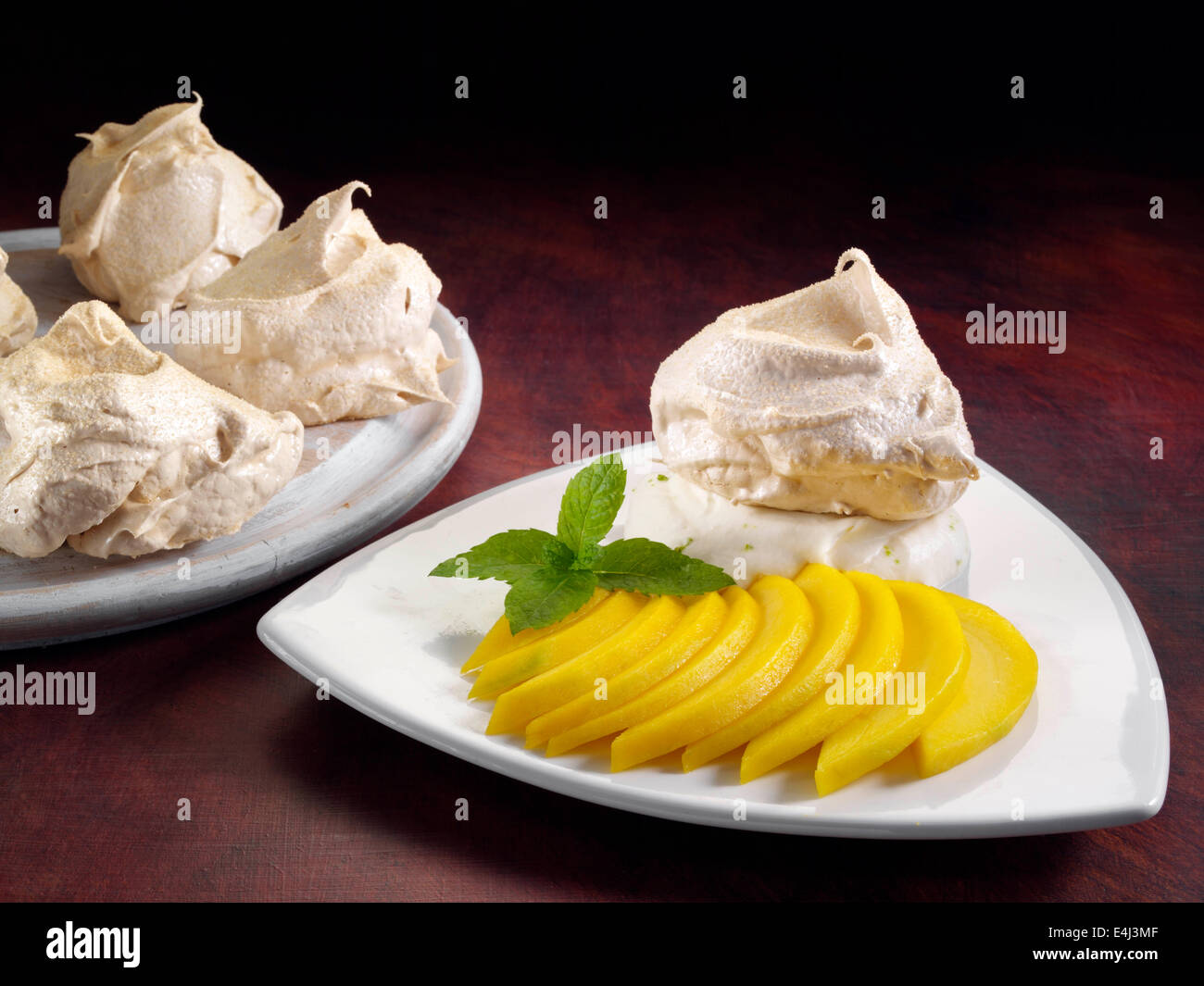 Muscavado meringhe con crema di calce e fette di mango Foto Stock