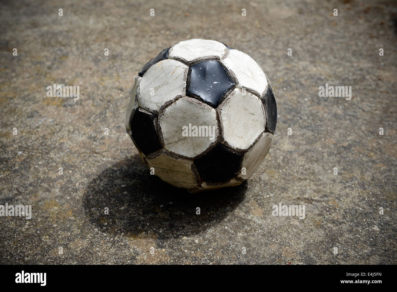 Vecchio e usato palla calcio su un cemento campo da gioco Foto Stock