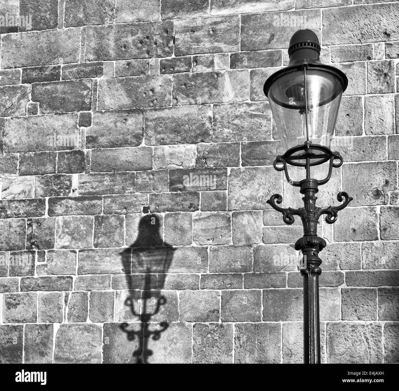 Vintage lanterna di strada con la sua ombra su un vecchio muro della chiesa Foto Stock
