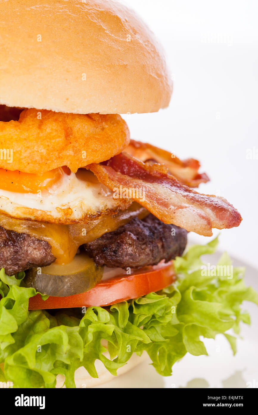 Deliziose uova e bacon cheeseburger con un riempimento nutrizionale di insalata ingredienti, una polpetta di carne macinata, formaggio, uova fritte e pancetta croccante su un bianco rotolo croccante Foto Stock