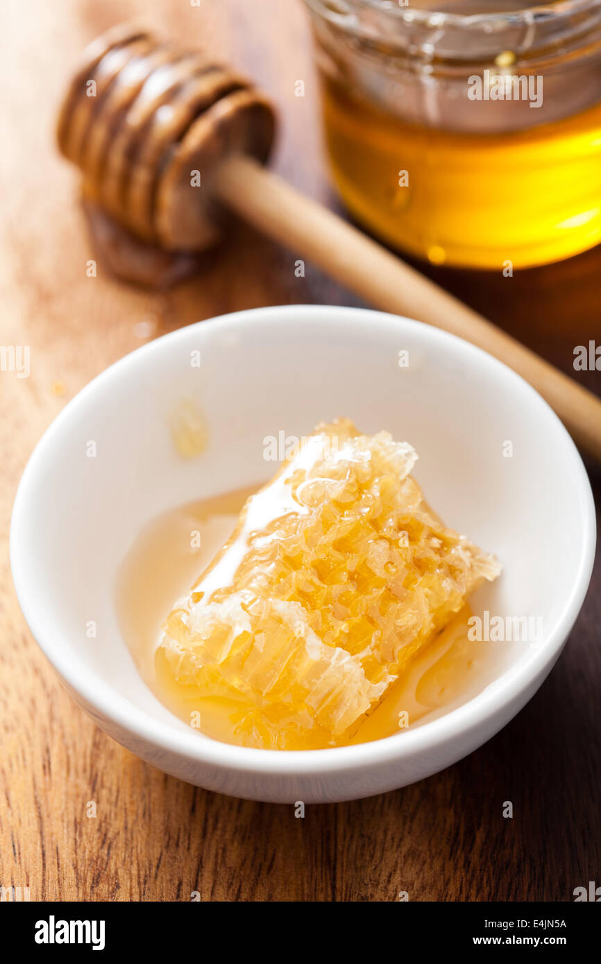Nido e miele in vaso su sfondo di legno Foto Stock