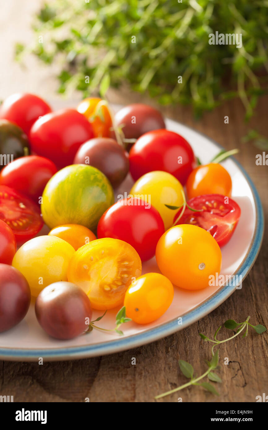 Pomodori colorati nella piastra su sfondo di legno Foto Stock