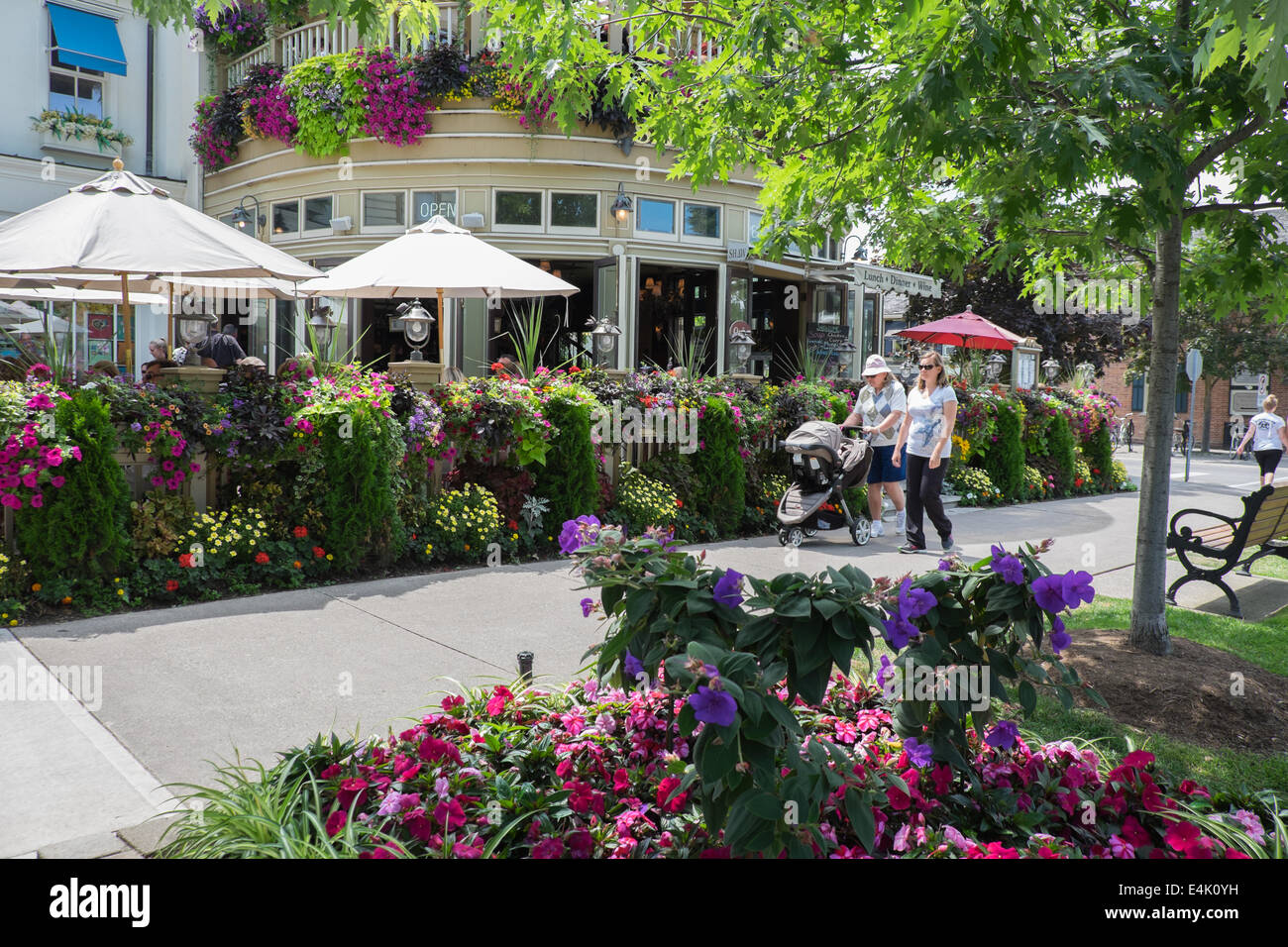 I turisti a piedi da una delle molte colorate composizioni floreali che può essere trovato nel centro storico della città vecchia di Niagara sul Lago Ontario, Canada. Foto Stock