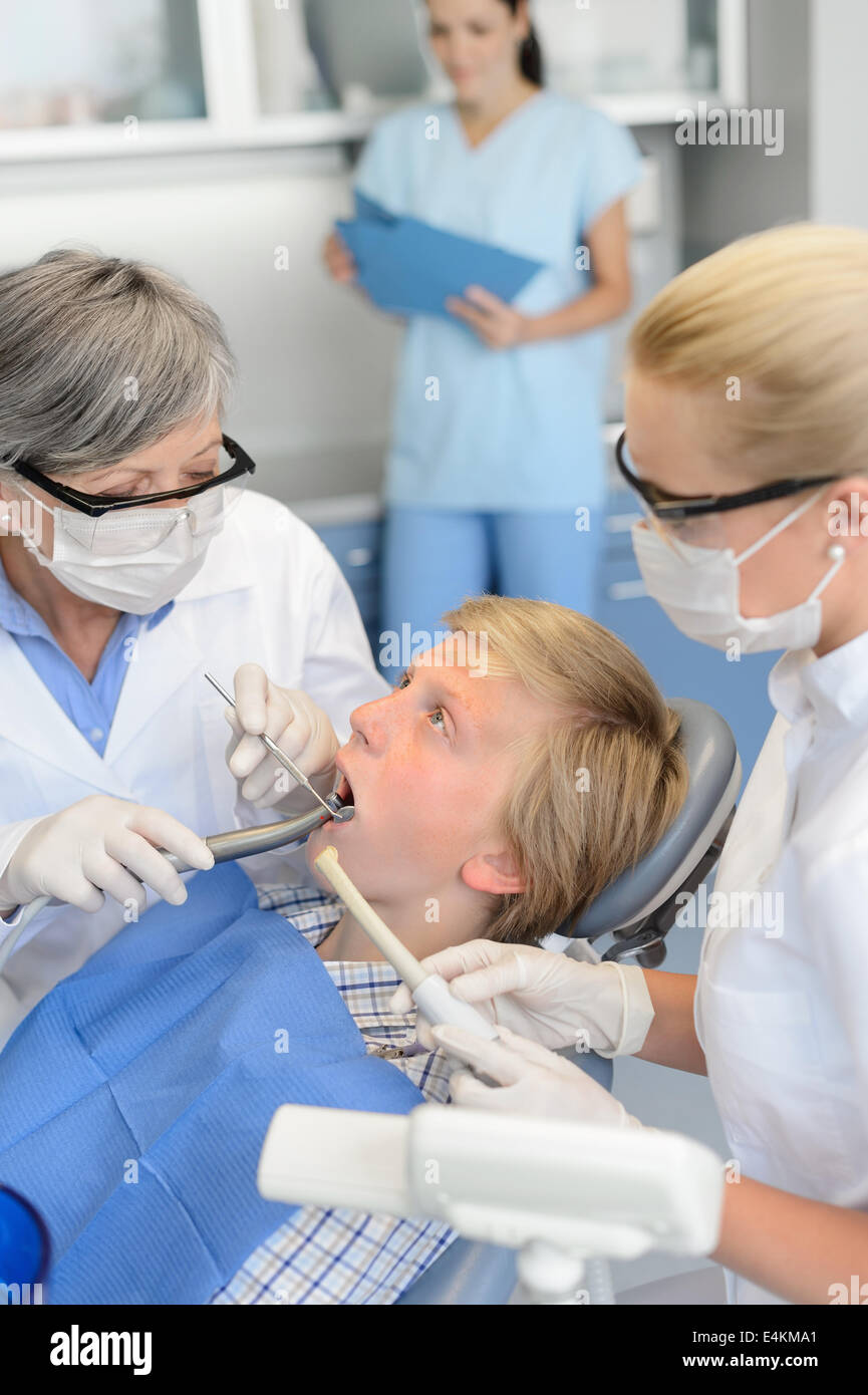 Dentista con l'infermiera di trattamento sul paziente adolescente a un intervento di chirurgia dentale Foto Stock