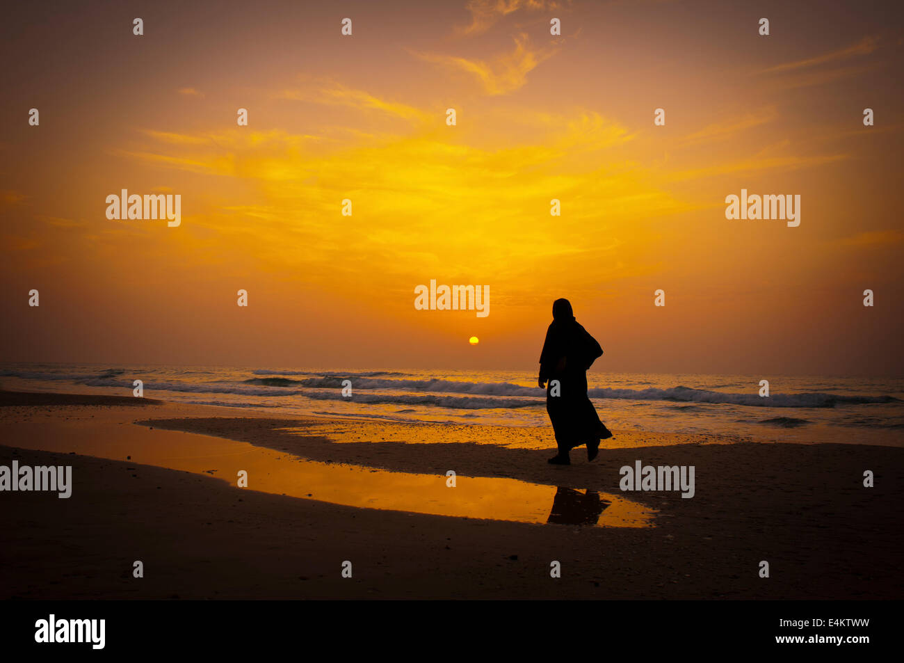 Silhouette di una donna su una spiaggia mediterranea al tramonto Foto Stock