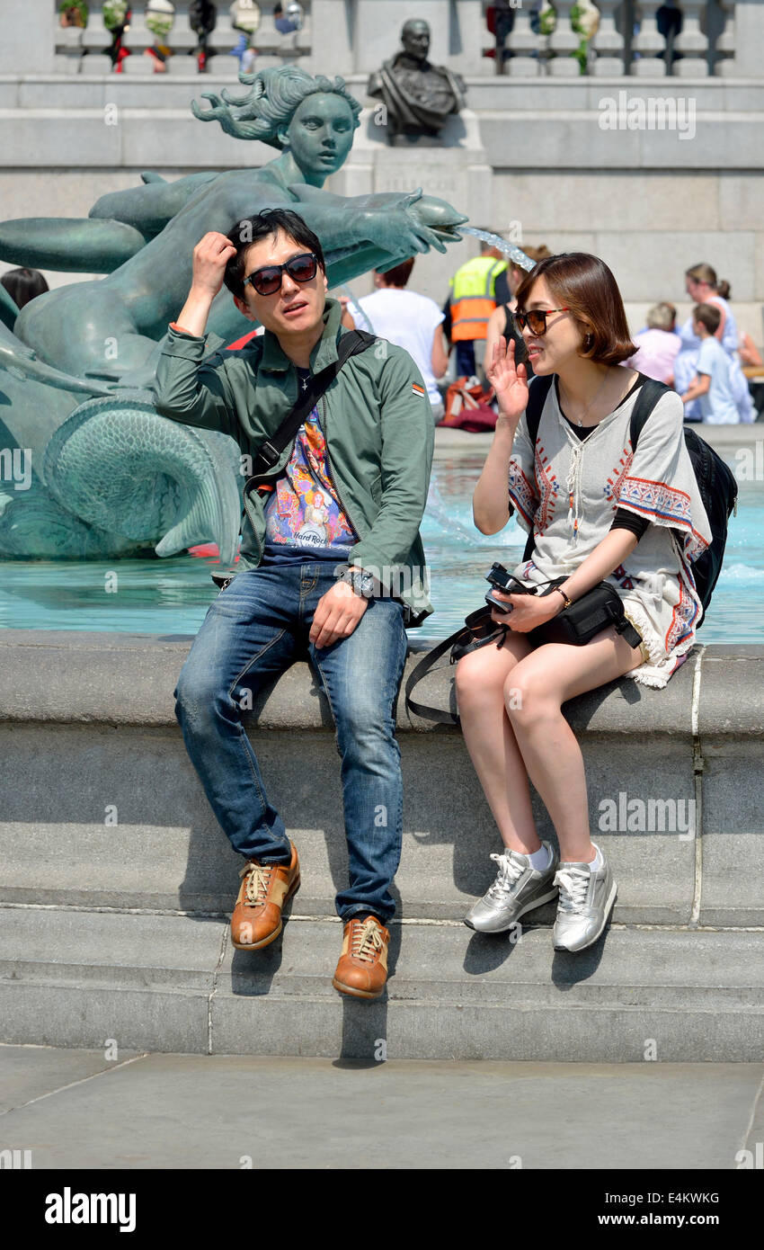 Londra, Inghilterra, Regno Unito. Giovani asiatici giovane rilassante in Trafalgar Square Foto Stock