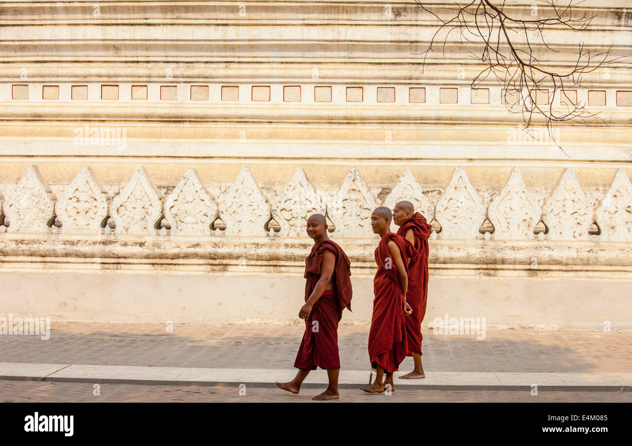 Tre monaci a piedi da un gigante pagoda buddista a Mandalay, Myanmar. Foto Stock