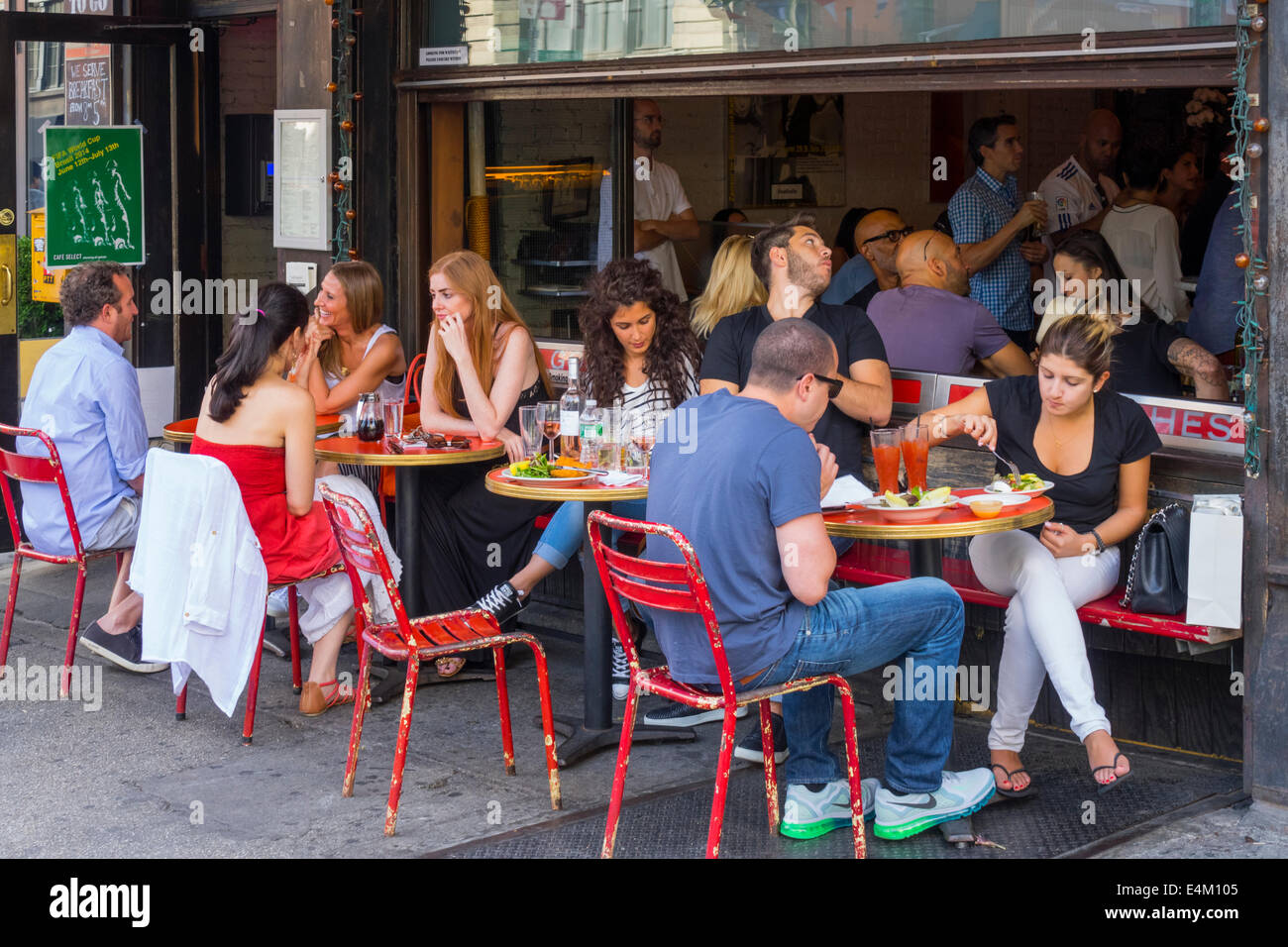 I giovani adulti in una caffetteria di mangiare al fresco in Soho a New York City Foto Stock