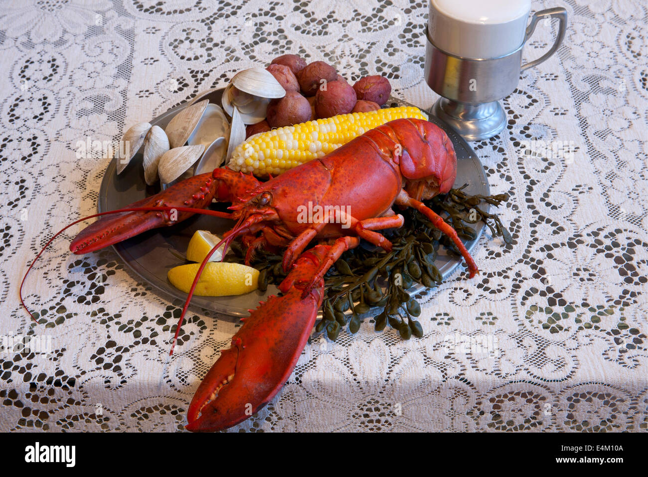 Tradizionale New England Clambake compresi aragosta, vongole, patate e sulla pannocchia di mais su una piastra in peltro con un stein di birra. Foto Stock