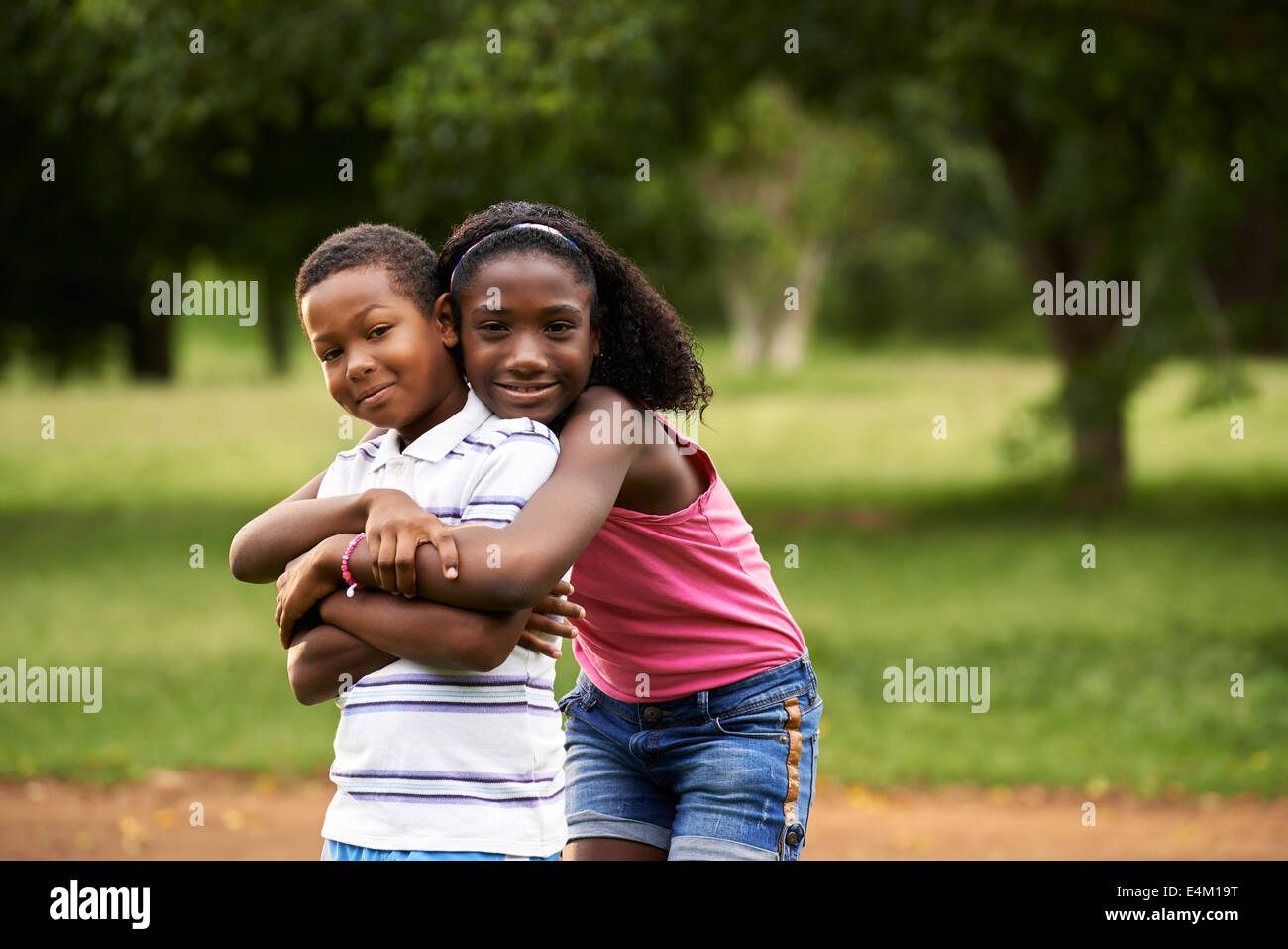 Persone in amore con il piccolo felice nero ragazza e ragazzo abbracciando e abbracciando nella city park Foto Stock